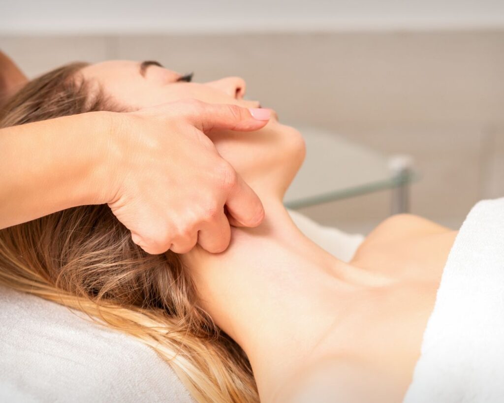 Close-up of hands gently massaging lymph nodes on a client's neck.