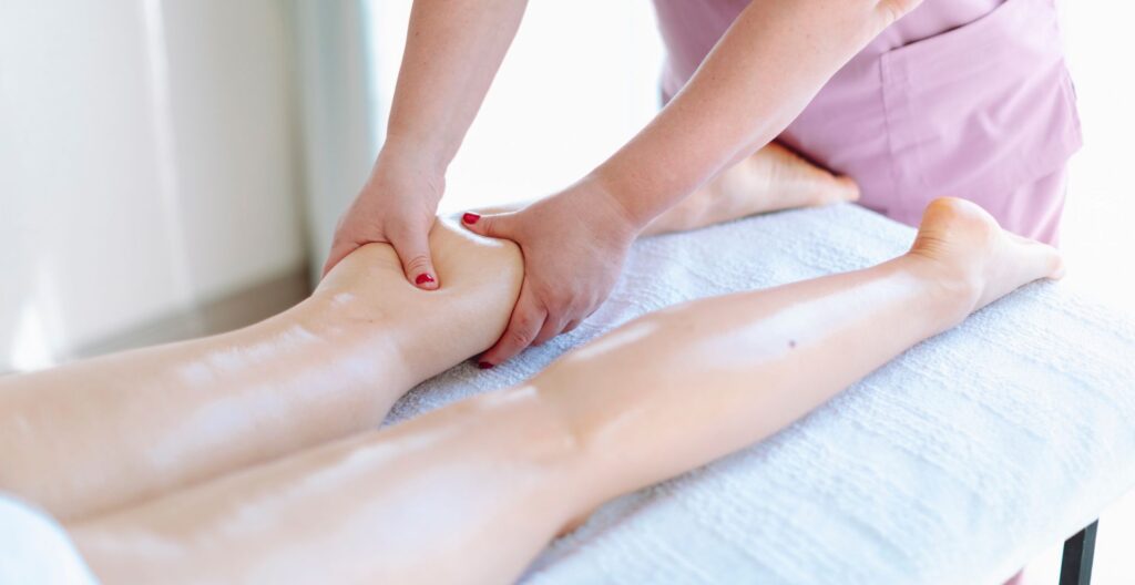 A certified therapist performing a lymphatic drainage massage on a client’s leg.